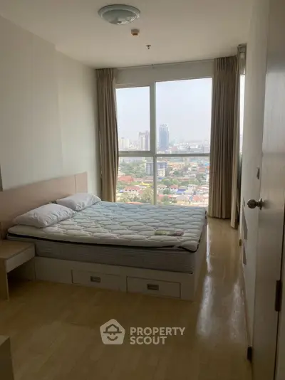 Cozy bedroom with city view, featuring a comfortable bed and large window for natural light.