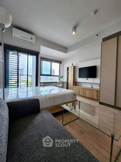 Modern bedroom with city view, featuring sleek furniture and a wall-mounted TV, perfect for urban living.