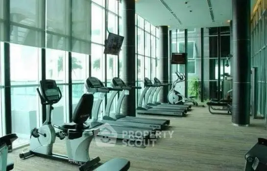 Luxurious gym with modern equipment and floor-to-ceiling windows offering stunning views.