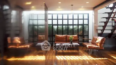Stylish living room with leather seating and large windows, featuring modern design and natural light.