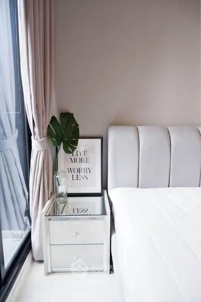 Modern bedroom with elegant decor, featuring a plush bed, mirrored nightstand, and large window with curtains.