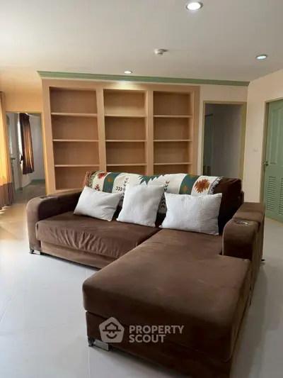 Spacious living room with brown sectional sofa and built-in wooden shelves