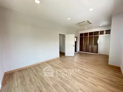 Spacious empty bedroom with wooden flooring and built-in wardrobe