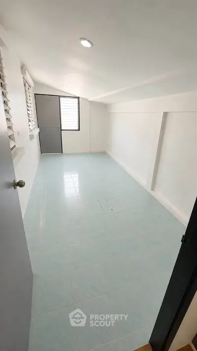 Spacious empty room with tiled floor and natural light, perfect for customization.