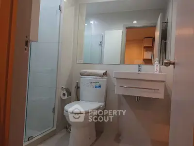 Modern bathroom with glass shower and sleek fixtures in contemporary apartment.