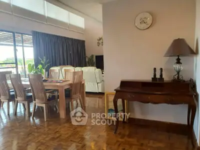 Spacious living room with elegant dining area and large windows offering natural light.