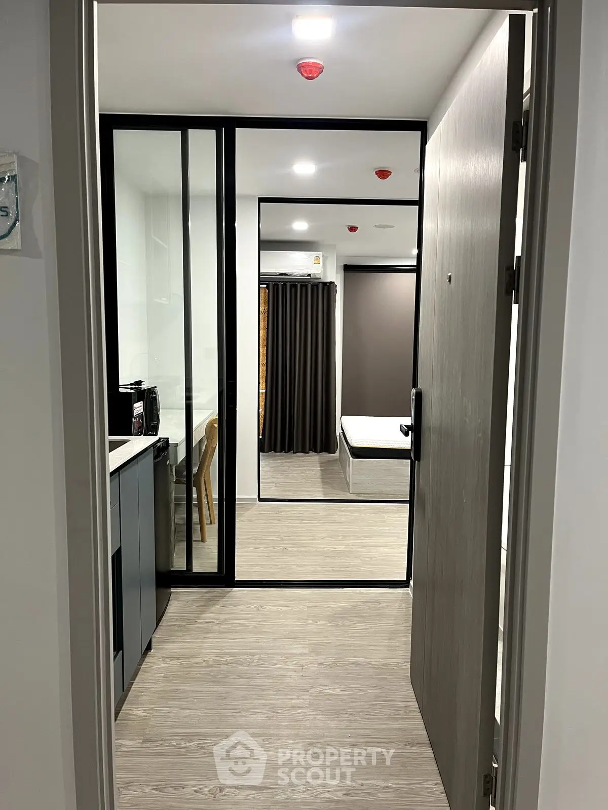 Modern apartment entrance with sleek kitchen and cozy bedroom view.