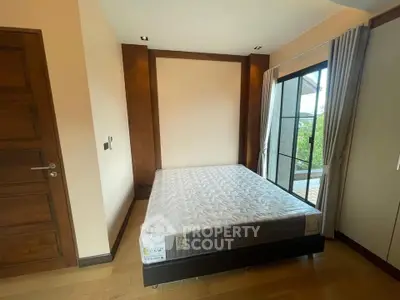 Cozy bedroom with large window and modern decor, offering a serene and inviting atmosphere.