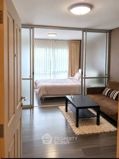 Modern studio apartment with cozy living area and bedroom separated by glass sliding doors.