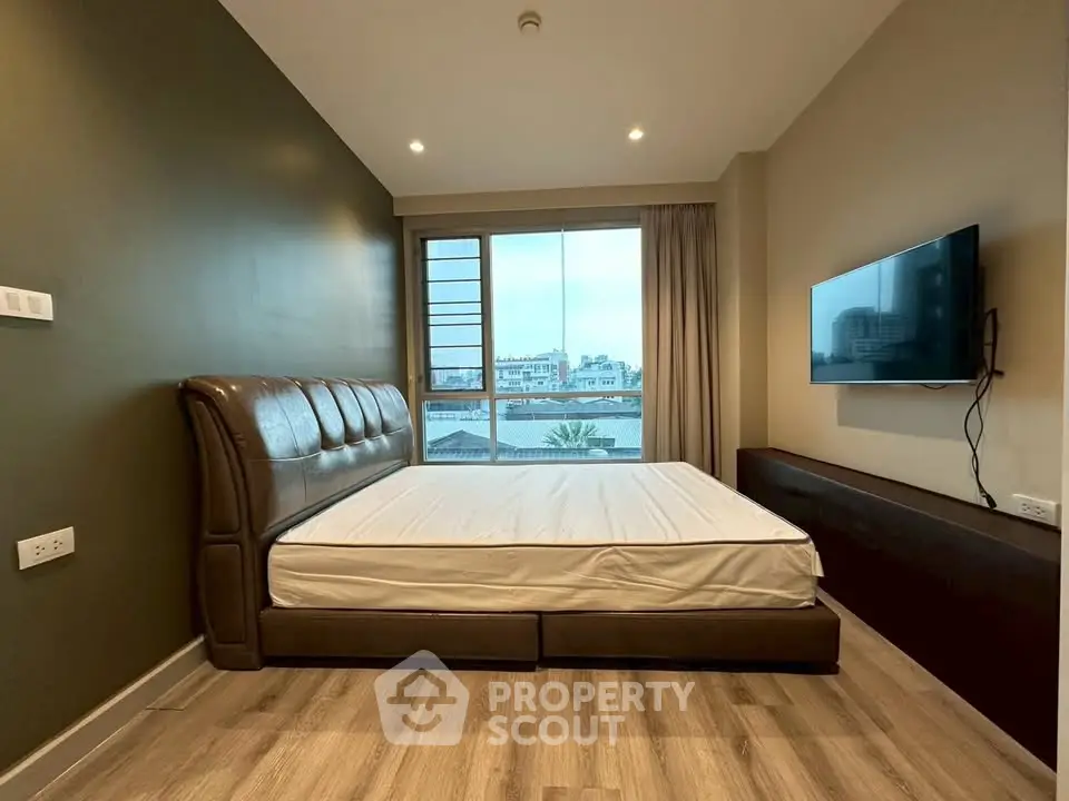 Modern bedroom with large window and wall-mounted TV in urban apartment