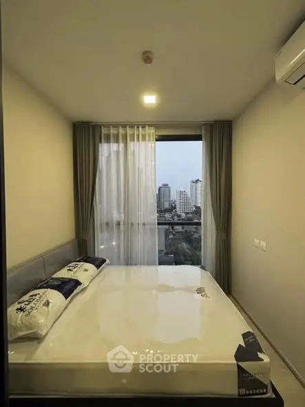 Modern bedroom with city view, featuring a large window and air conditioning unit.