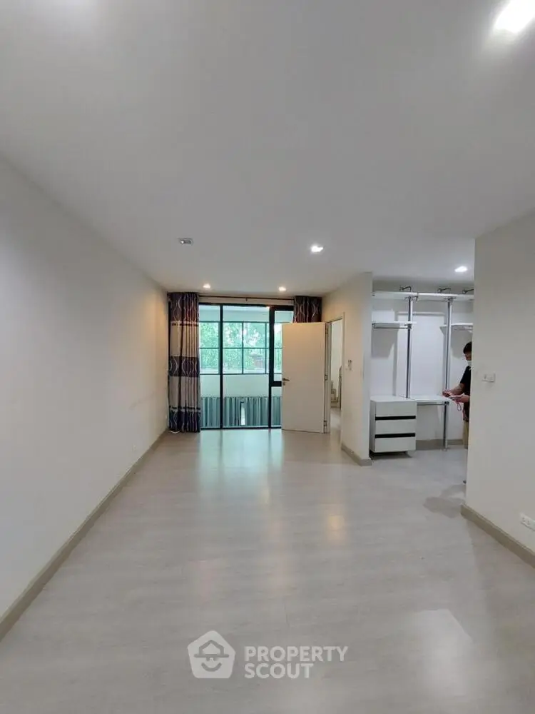Spacious empty room with large window and modern flooring, perfect for customization.