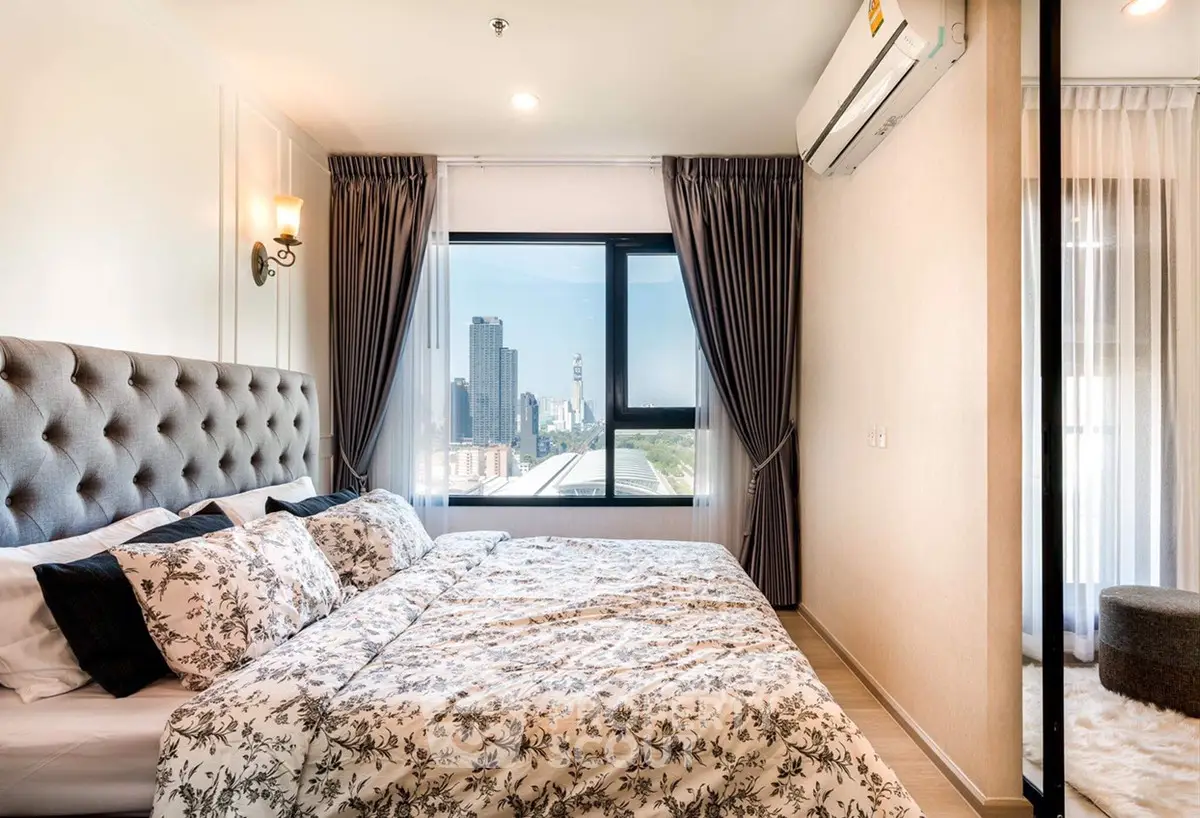 Luxurious bedroom with city view, elegant decor, and ample natural light.