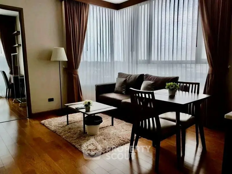 Elegant living room with hardwood floors, cozy sofa, and dining area in modern apartment.
