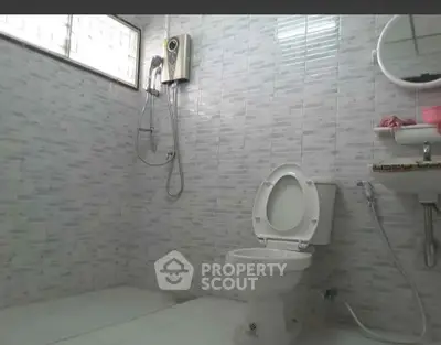 Spacious bathroom with modern fixtures and tiled walls, featuring a shower and toilet.