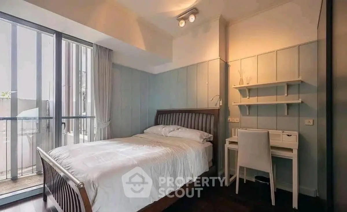Cozy bedroom with modern design and balcony access, featuring a comfortable bed and study desk.