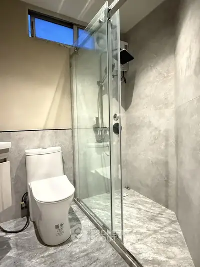 Modern bathroom with glass shower and sleek toilet in a stylish apartment.