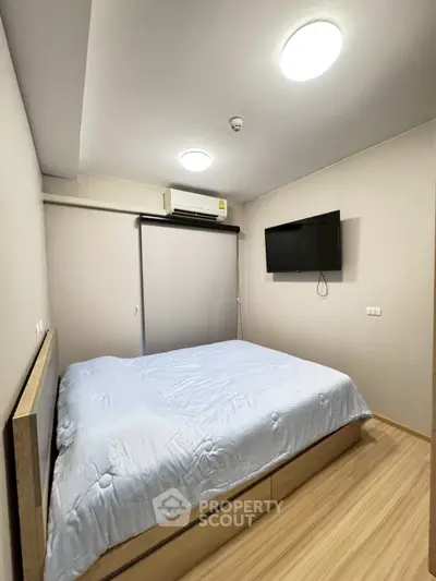 Cozy bedroom with modern decor and wall-mounted TV, perfect for relaxation.