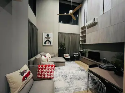 Modern living room with high ceiling, stylish decor, and cozy seating area