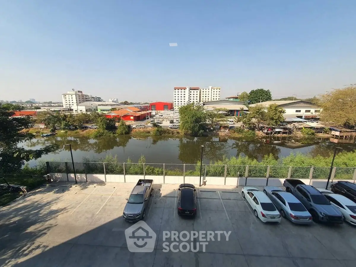 Scenic view from a parking lot overlooking a serene pond and urban landscape.