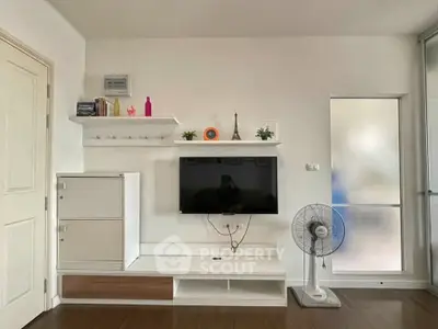 Modern living room with wall-mounted TV and stylish shelving in a cozy apartment.