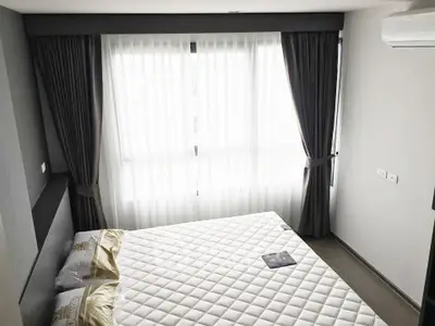 Modern bedroom with large window and elegant curtains, featuring a comfortable bed and air conditioning.