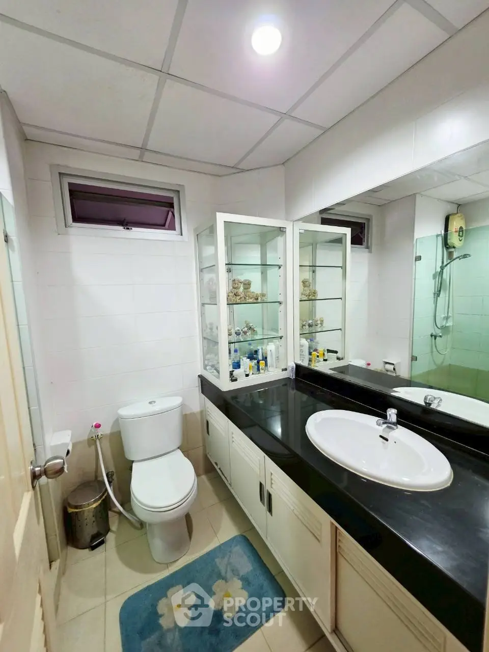 Modern bathroom with sleek black countertop and glass cabinet storage.