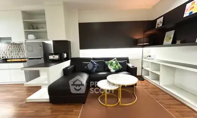 Modern living room with sleek black sofa, stylish coffee tables, and open kitchen layout.