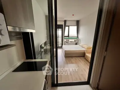 Modern studio apartment with sleek kitchen and cozy bedroom, featuring large windows and stylish decor.