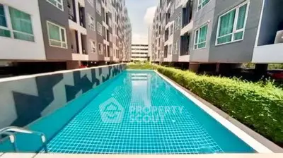 Modern apartment complex with a sleek swimming pool and lush greenery.