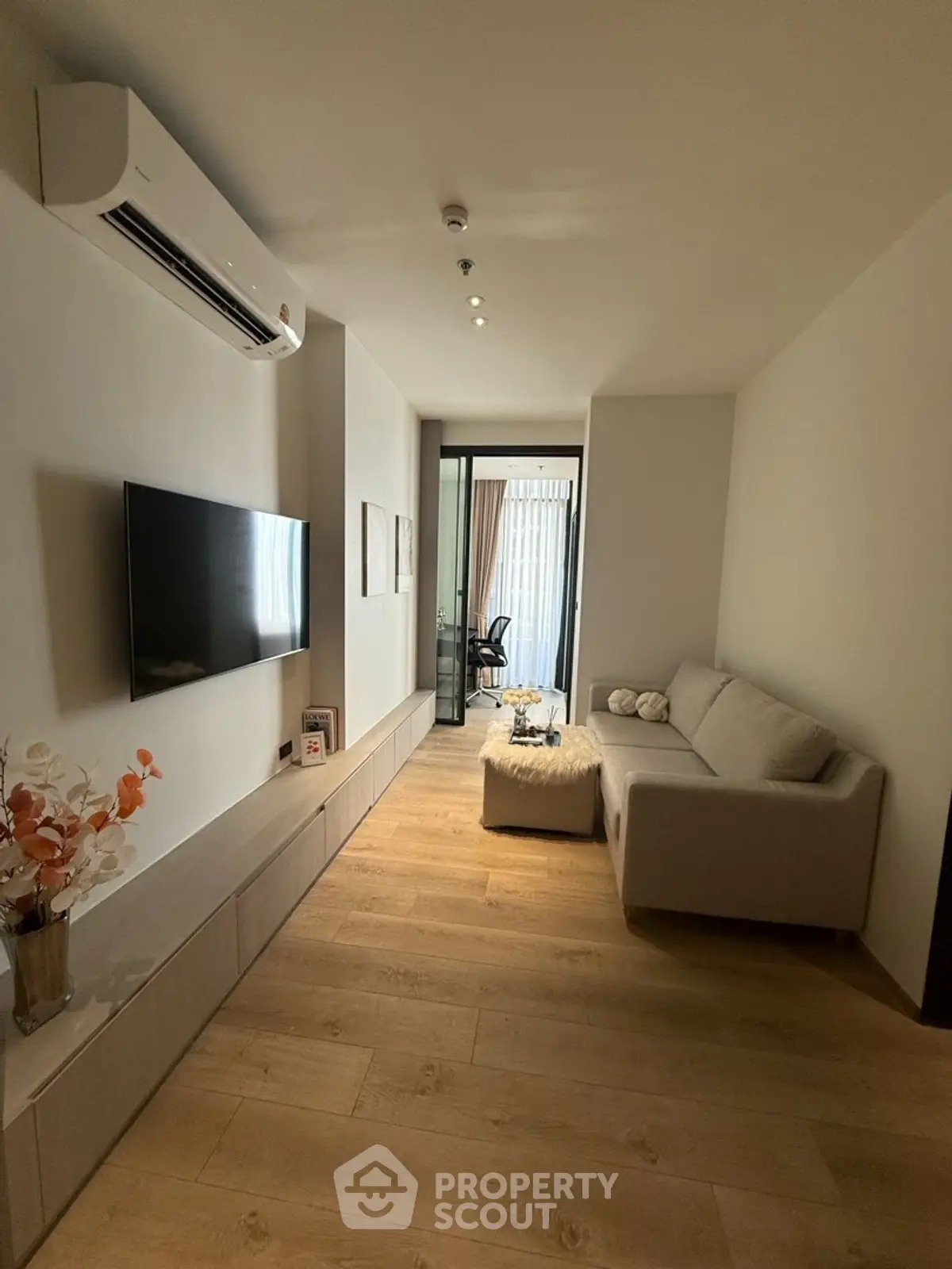 Modern living room with sleek design, featuring a wall-mounted TV, cozy sofa, and elegant wooden flooring.