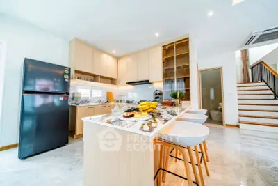 Modern kitchen with marble island and sleek appliances in a bright open space.