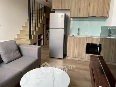 Modern loft-style living room with sleek kitchen and wooden staircase