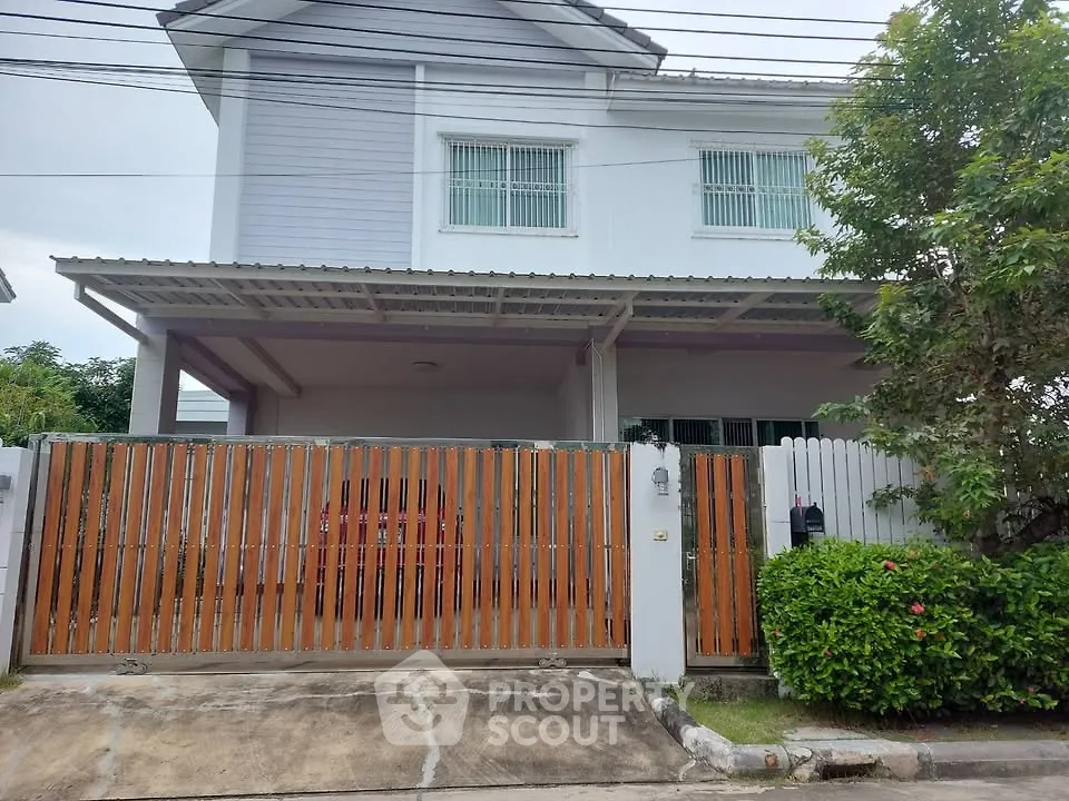 Charming two-story house with gated entrance and lush greenery, perfect for family living.