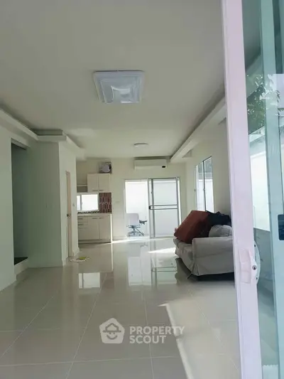 Spacious modern living room with sleek tile flooring and open kitchen layout.