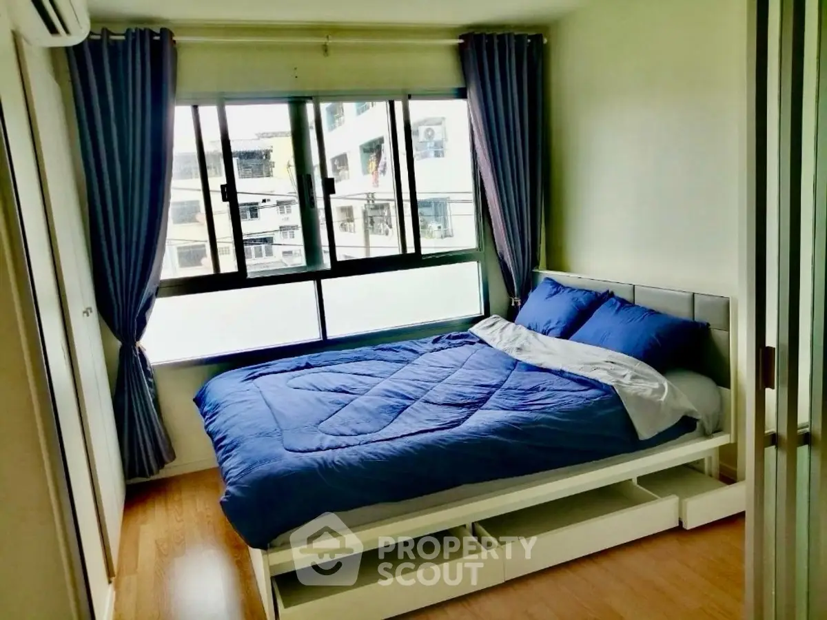 Cozy bedroom with blue bedding and large window in modern apartment