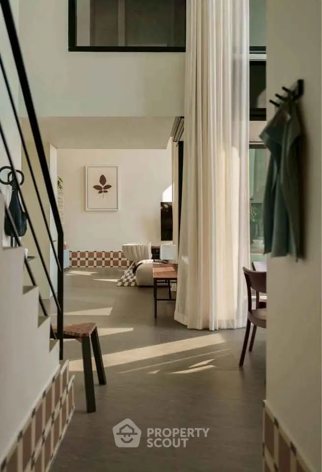 Modern living room with high ceilings and elegant decor, featuring natural light and stylish furniture.