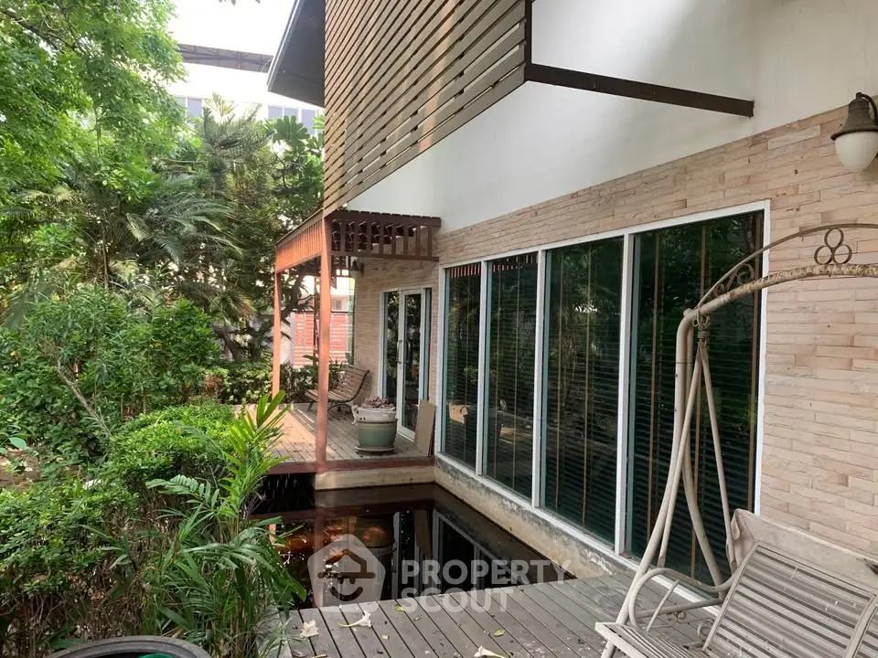 Charming home exterior with lush garden and spacious wooden deck, perfect for outdoor relaxation.