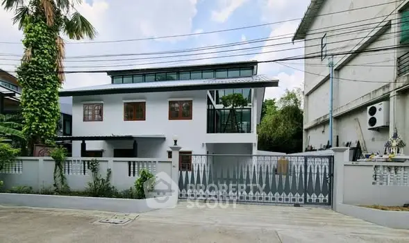 Modern two-story house with sleek design and gated entrance in urban setting.