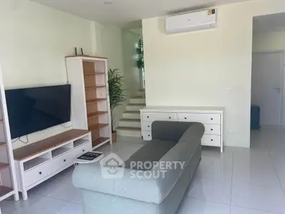 Modern living room with sleek furniture and air conditioning, featuring a cozy sofa and stylish shelving.