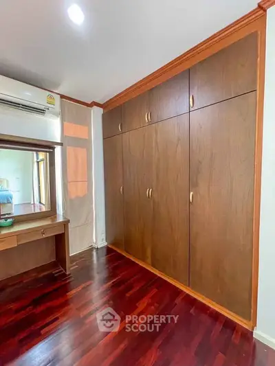 Spacious bedroom with wooden wardrobe and elegant hardwood flooring