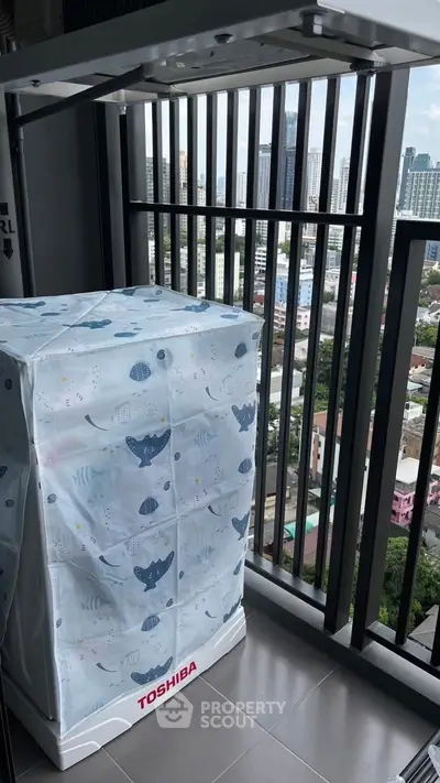 High-rise balcony with city view and covered washing machine, perfect for urban living.