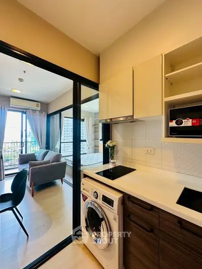 Modern apartment with open kitchen and cozy living area, featuring a washing machine and stylish decor.