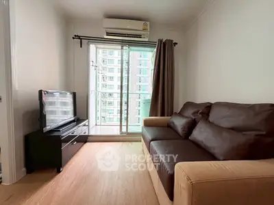 Cozy living room with modern sofa and TV, featuring a balcony view in a high-rise apartment.