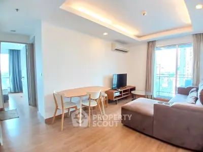 Spacious living room with modern furniture and natural light in a high-rise apartment.
