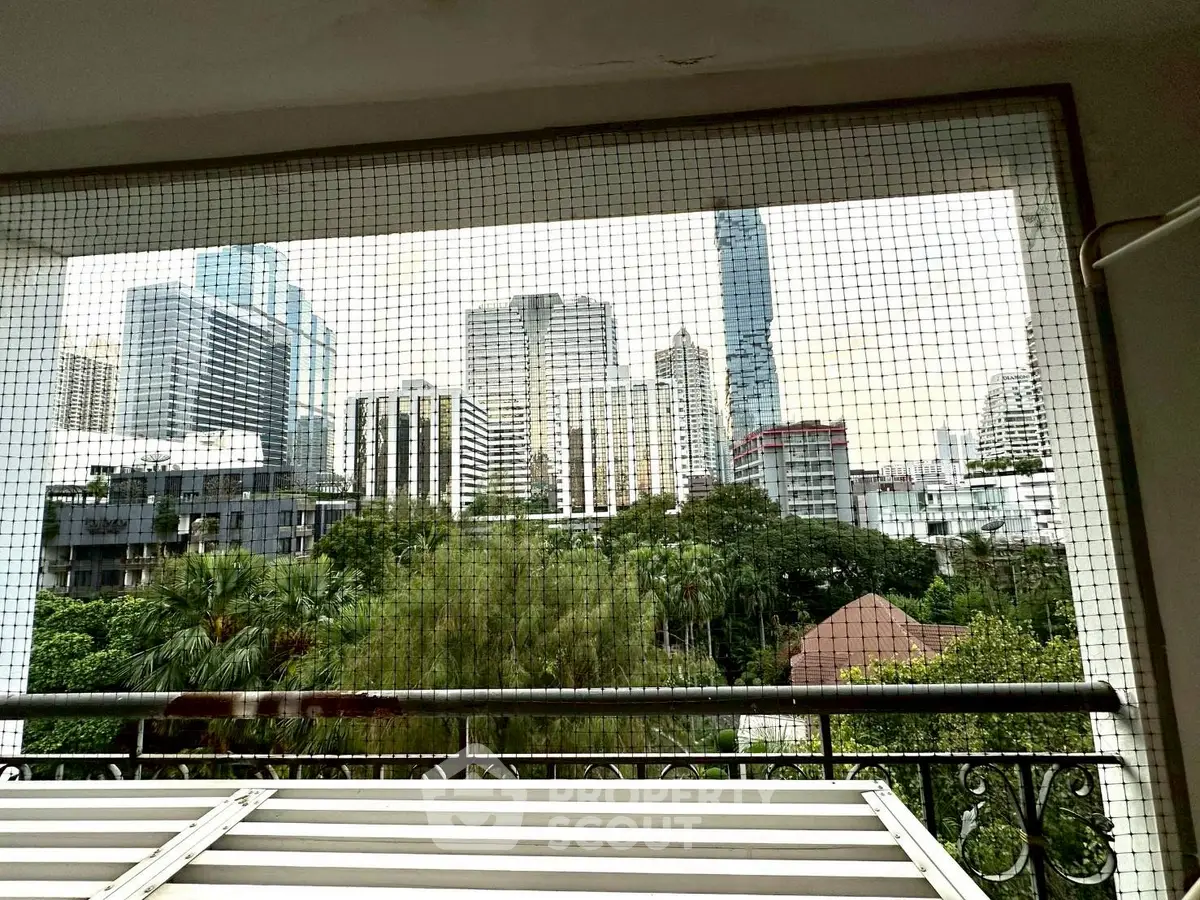 Stunning city view from a balcony with lush greenery and skyline backdrop.
