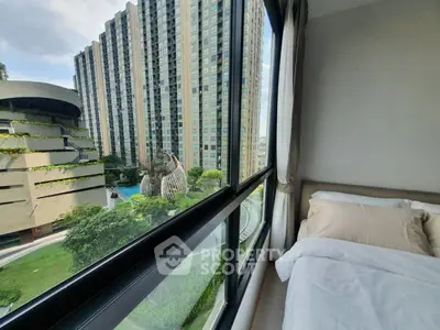 Modern bedroom with large window offering stunning cityscape view