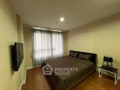 Cozy bedroom with modern decor and natural light from large window, perfect for relaxation.
