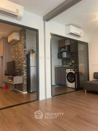 Modern apartment interior with open layout, featuring a kitchen with appliances and a cozy living area.