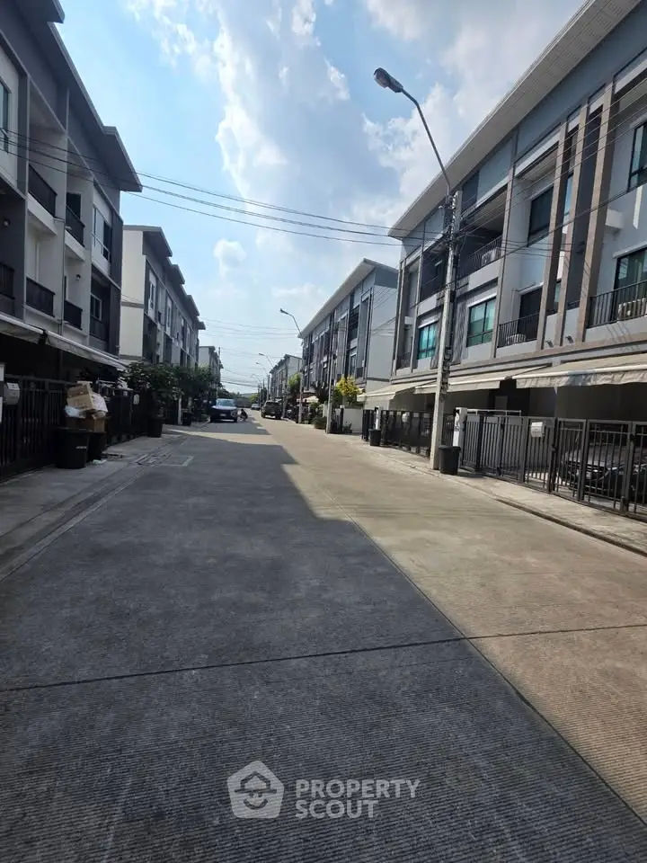 Modern townhouse street view with clear sky and contemporary architecture.